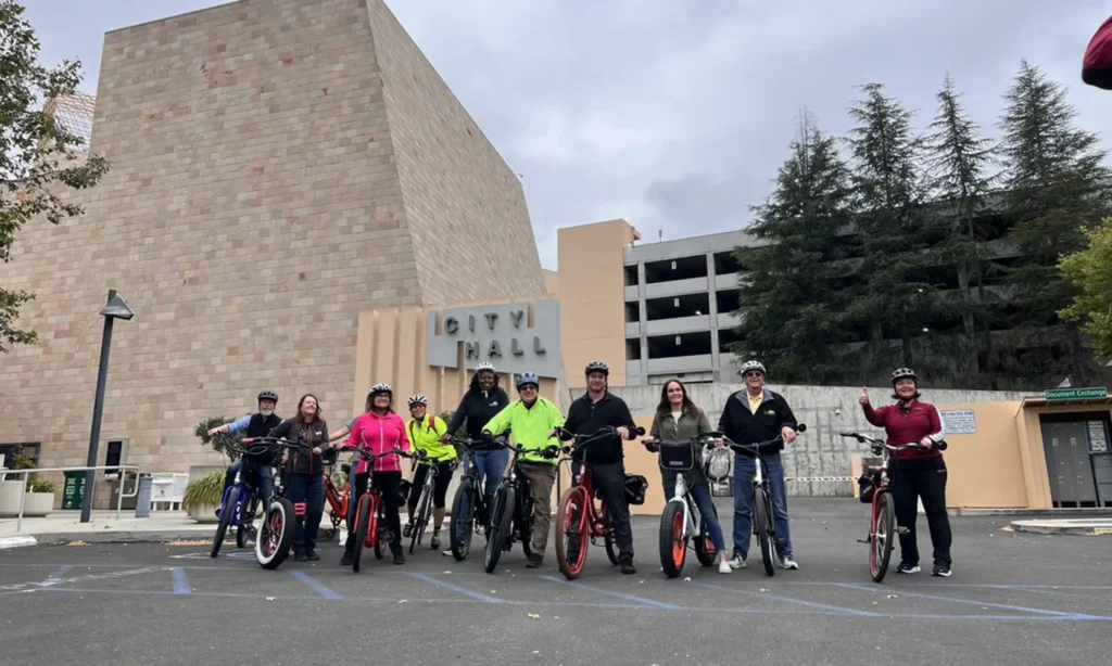 A group of people posing with bikes and wearing helmets outside of Thousand Oaks City Hall.