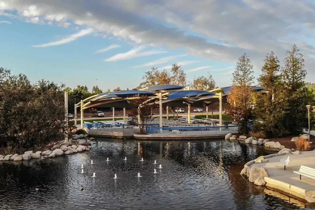 Covered picnic area with medium-sized man-made lake in view at sunset.