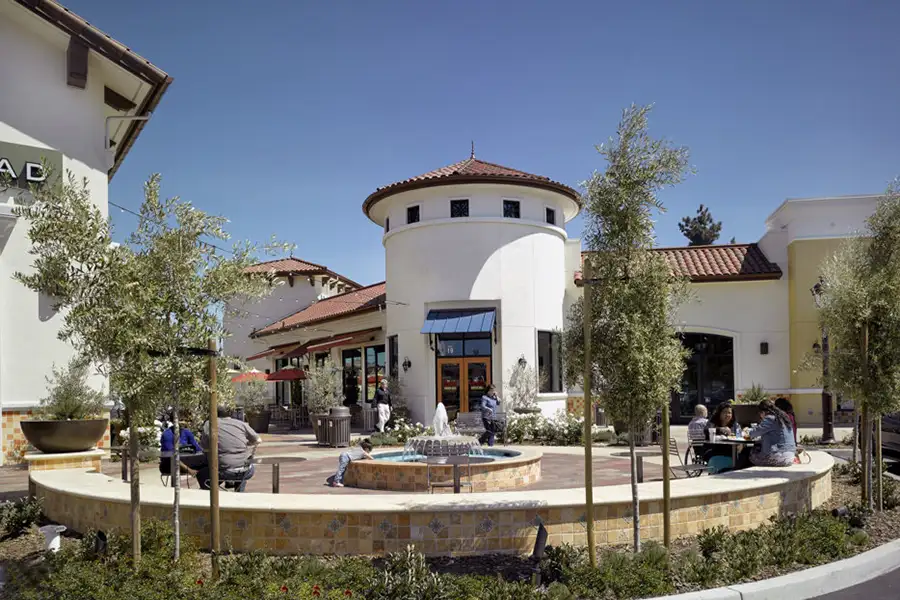 Circular plaza with fountain and surrounding building finished in a Spanish-style.