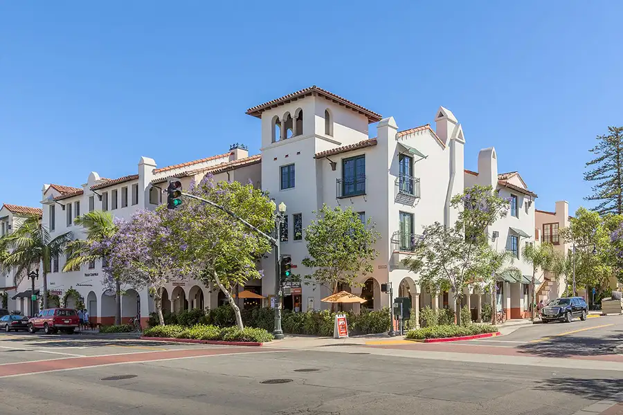 Mixed-use apartment building finished in a Spanish style taken from a street corner.