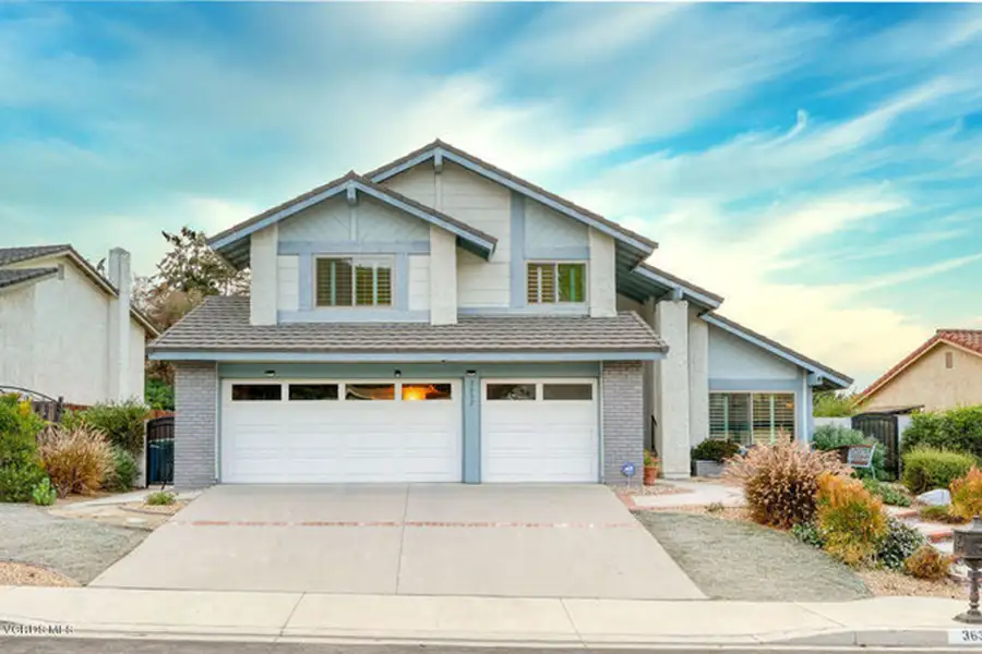 Two-story single family home painted in light-blue and gray. The edges of two adjacent homes are seen.