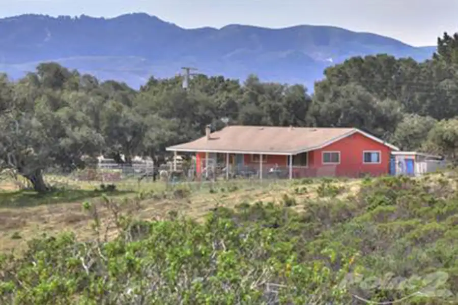 Lone smaller house on a large plot of land with farm animals alongside the house in a coral.