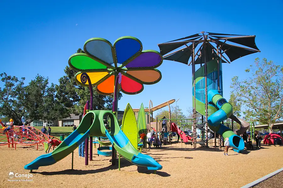 Playground with many slides and playground equipment with children playing on it.