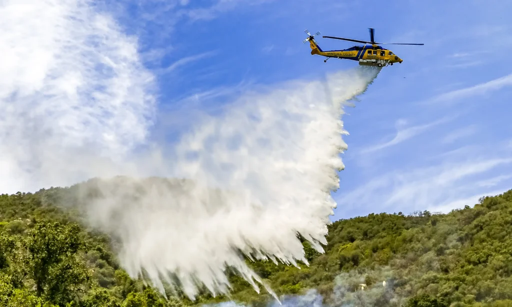 Ventura County Firefighting helicopter dropping water on a hillside fire.