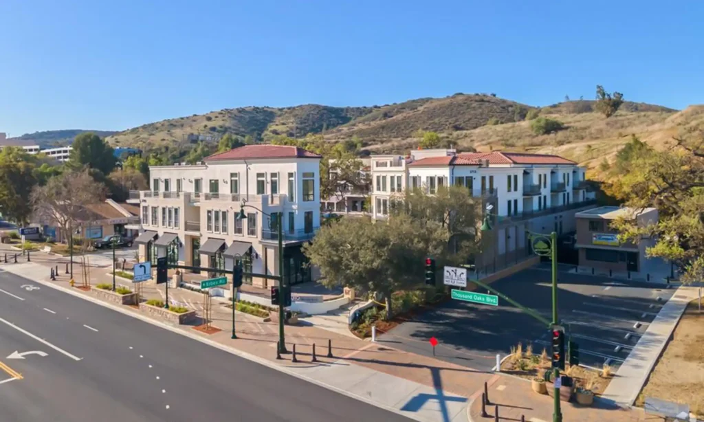 Newly-built mixed-use building standing three stories high along Thousand Oaks boulevard with hills behind it.