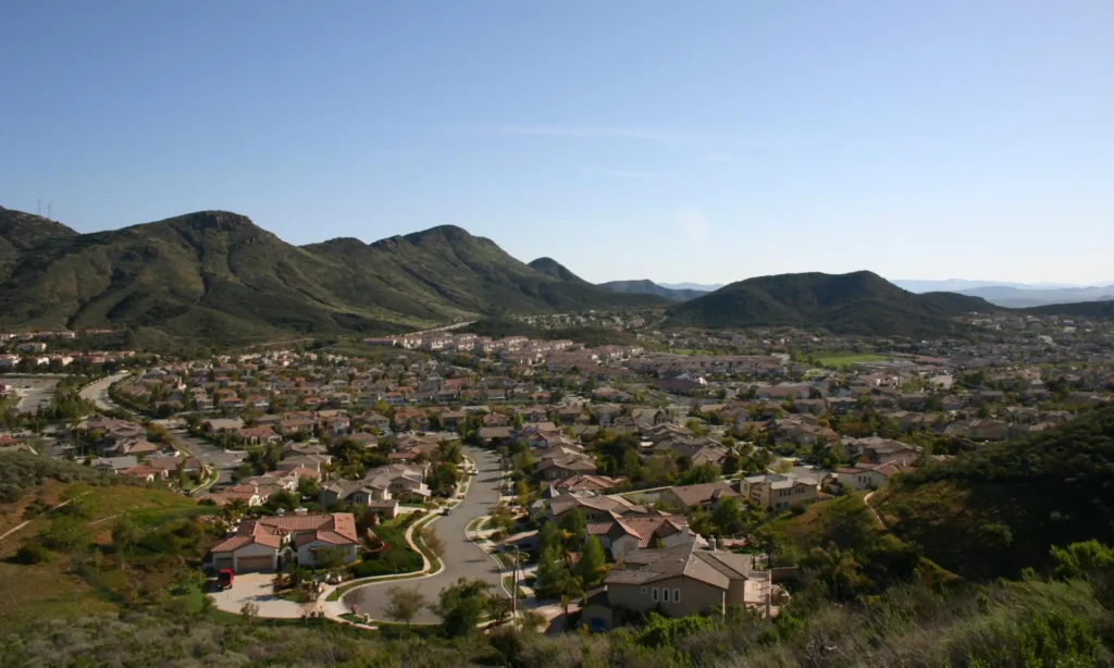 View from a highpoint of a surburban tract development with lots of single-family homes in view abutting hills.